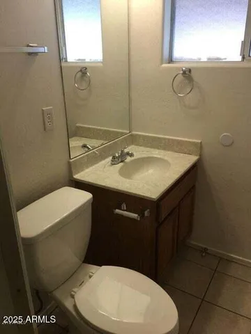 a bathroom with a granite countertop toilet sink and mirror
