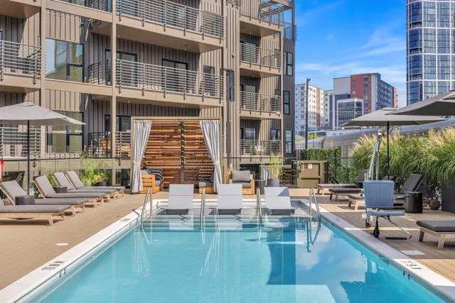 a view of a patio with couches table and chairs under an umbrella with a barbeque