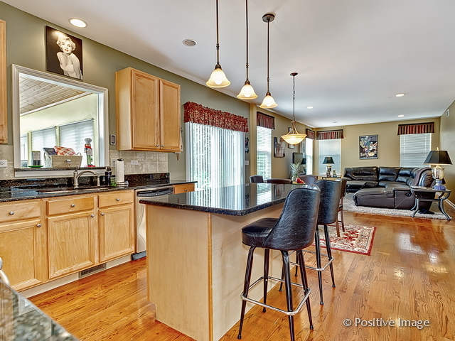 1463 Saddleridge Place Bartlett, IL 60103 - Photo 11 of 27 a large kitchen with stainless steel appliances kitchen island granite countertop a table chairs in it and a wooden floors