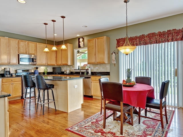 1463 Saddleridge Place Bartlett, IL 60103 - Photo 10 of 27 a kitchen with stainless steel appliances granite countertop a stove a sink a microwave a dining table and chairs