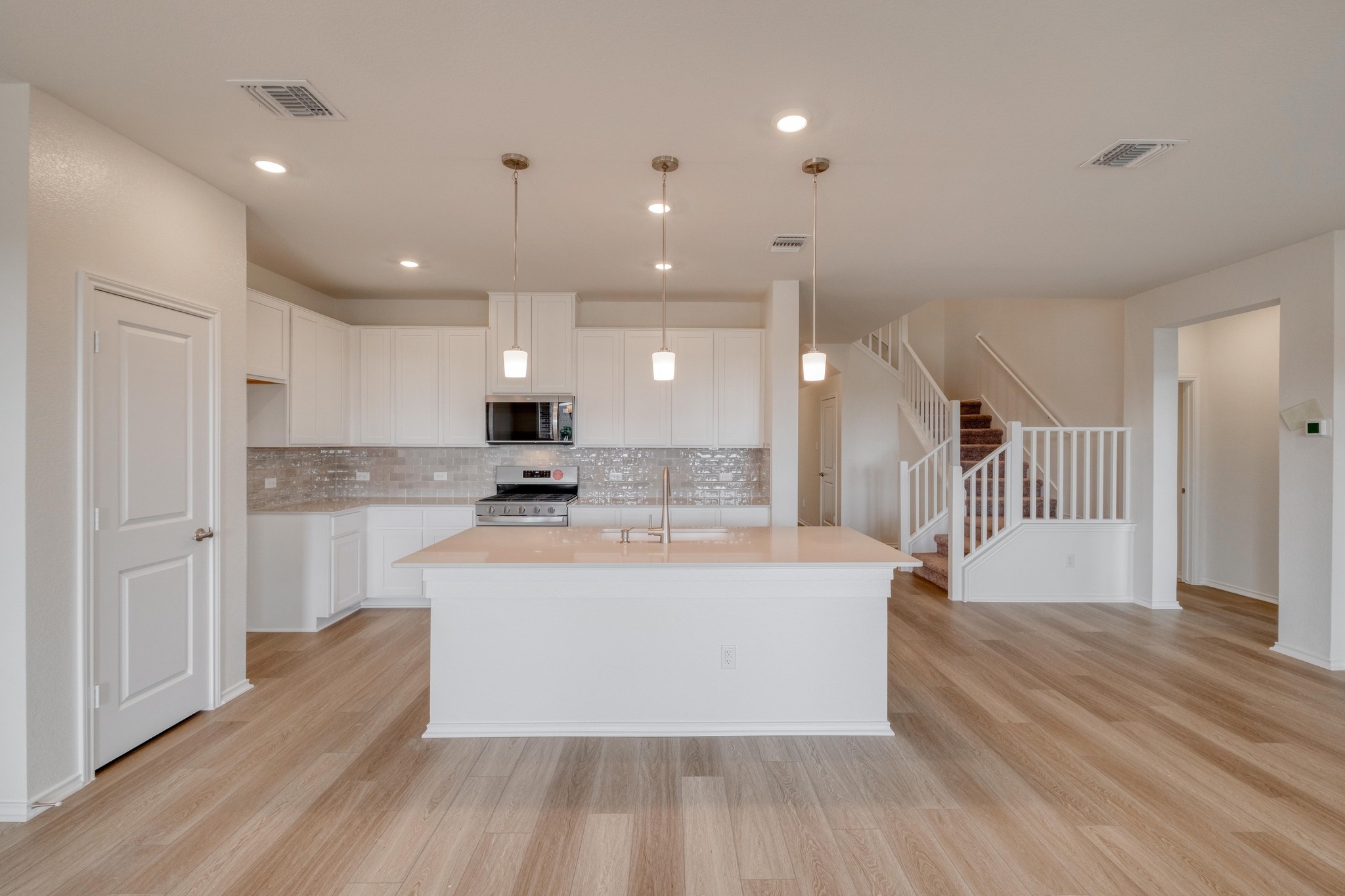 4608 Centola Loop Round Rock, TX 78665 - Photo 7 of 33 a large kitchen with kitchen island a stove a sink a refrigerator and a fireplace