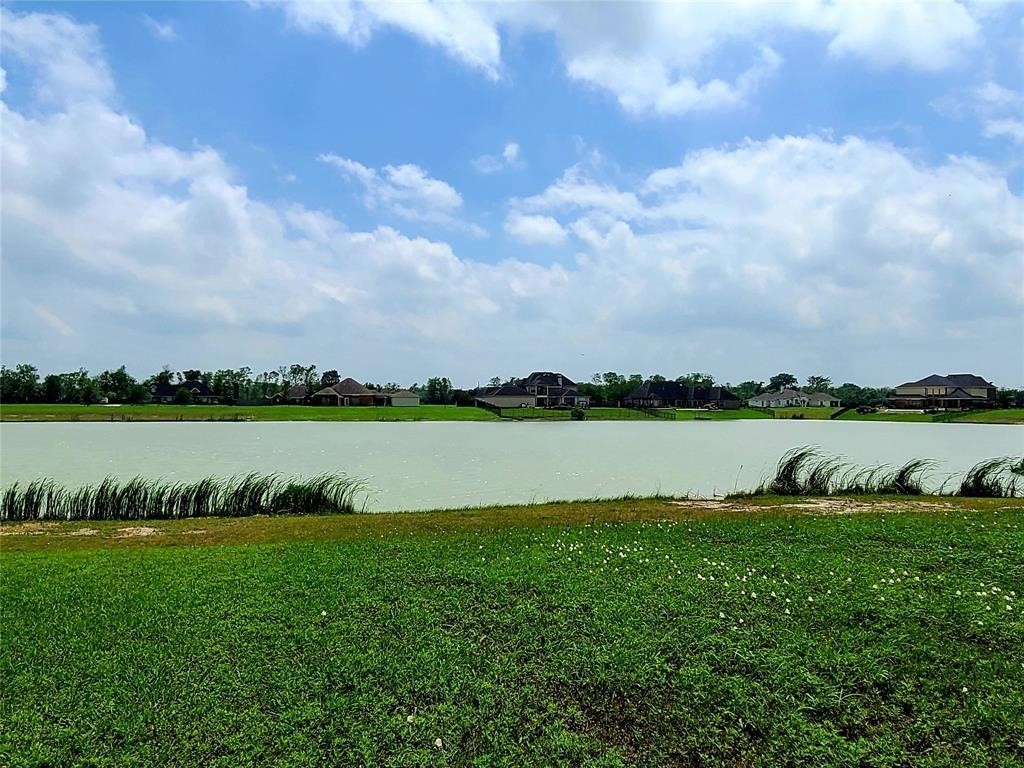 3711 Palm Crest Drive Rosharon, TX 77583 - Photo 7 of 9 This photo showcases a serene lakefront setting with a clear sky, lush green grass in the foreground, and houses visible across the water, offering a peaceful and picturesque view.