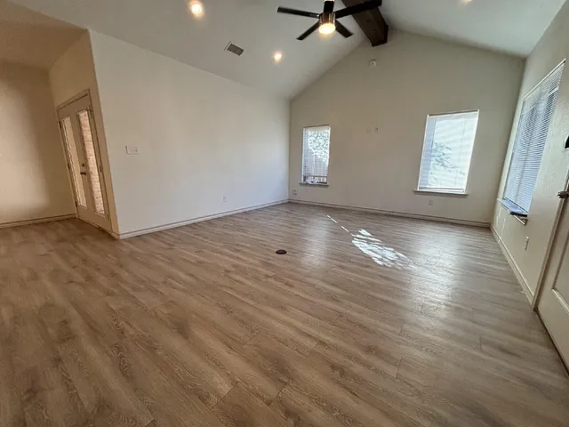 a view of an empty room with a window and wooden floor