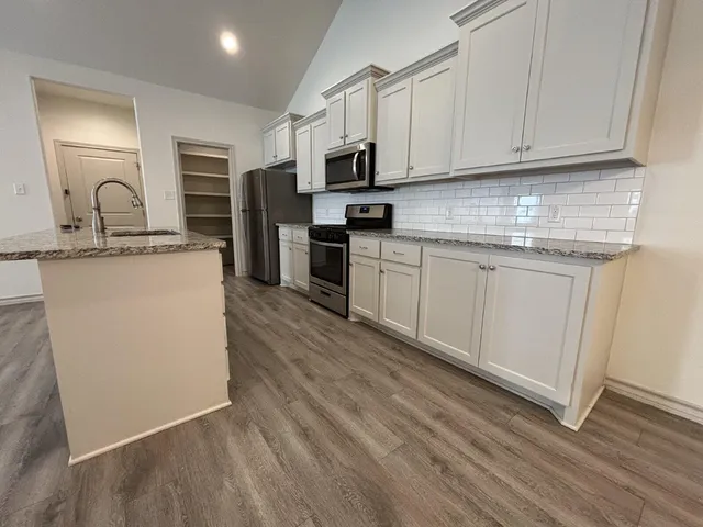a kitchen with granite countertop white cabinets and stainless steel appliances