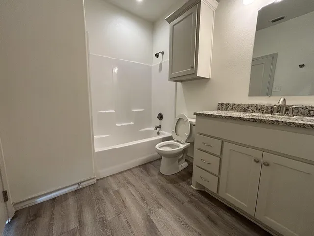 a bathroom with a granite countertop sink a toilet and bathtub