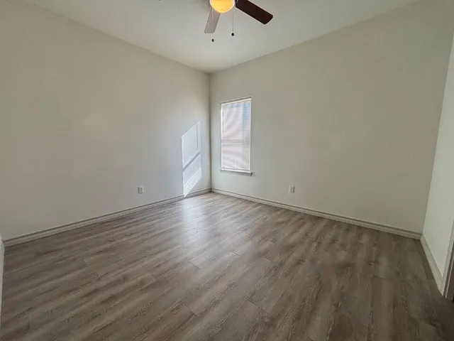 an empty room with wooden floor and chandelier fan
