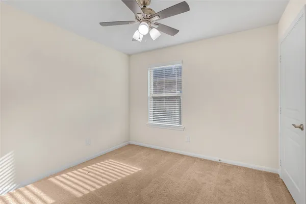an empty room with a window and a fan