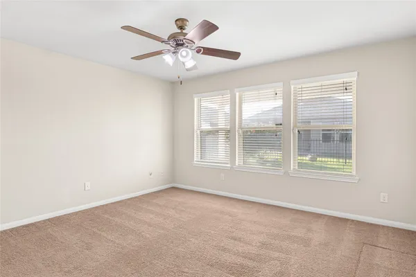 an empty room with a chandelier fan and windows