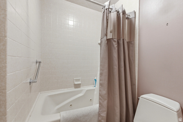 3674 Oak Rim Way Salt Lake City, UT 84109 - Photo 19 of 47 Bathroom featuring a white tiled shower surround, integrated grab bar, and a white soaking tub with jet features