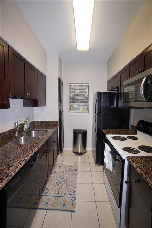 203 East 31st Street, Unit 103 Austin, TX 78705 - Photo 14 of 32 a kitchen with stainless steel appliances granite countertop a stove refrigerator sink and microwave