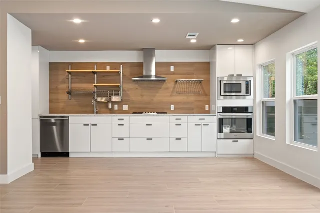 a large kitchen with stainless steel appliances kitchen island granite countertop a stove and a refrigerator