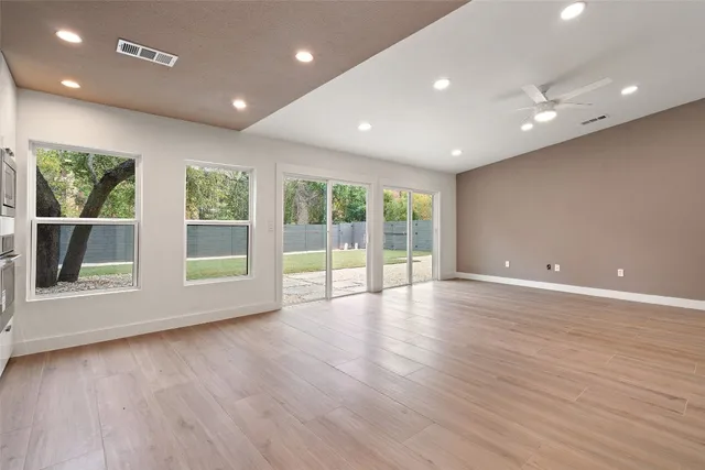 a view of empty room with wooden floor and fan