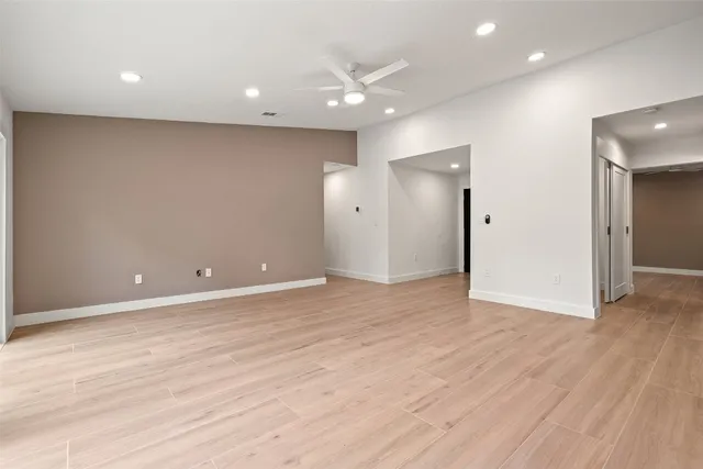 an empty room with wooden floor and a ceiling fan