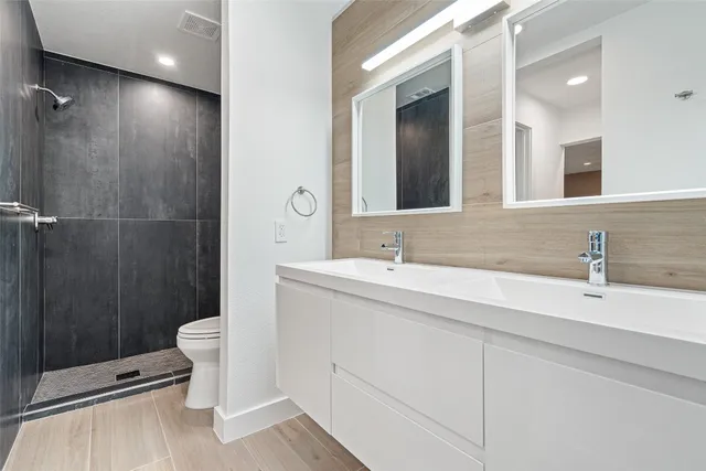 a bathroom with a double vanity sink toilet and shower