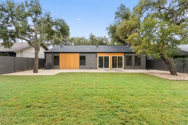 a backyard of a house with large trees and plants