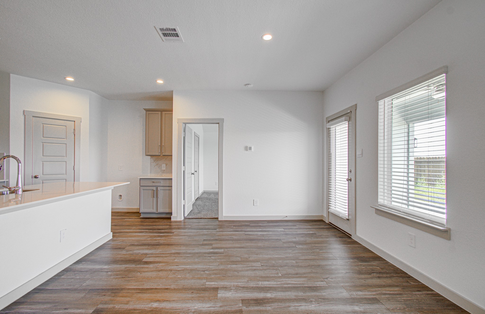 7903 Wrangler Shack Lane Rosharon, TX 77583 - Photo 17 of 29 Experience modern living in this bright, open space featuring sleek hardwood floors, a chic kitchen with white countertops, and abundant natural light streaming through large windows and a glass door to the outdoors.