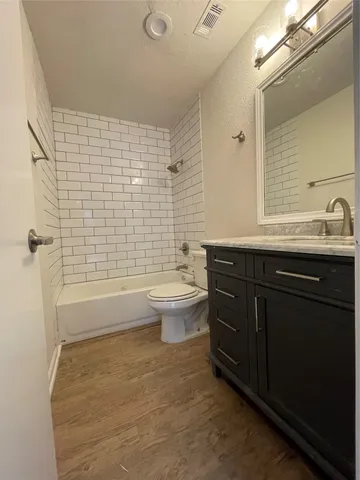 a bathroom with a granite countertop toilet a sink a mirror and shower