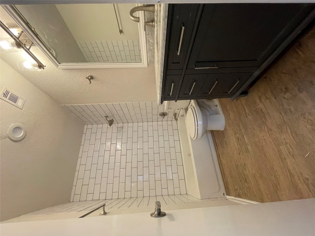 8806 Schick Road, Unit A Austin, TX 78729 - Photo 3 of 13 a bathroom with a granite countertop toilet a sink a mirror and shower