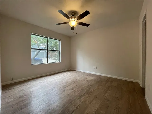 an empty room with ceiling fan and windows