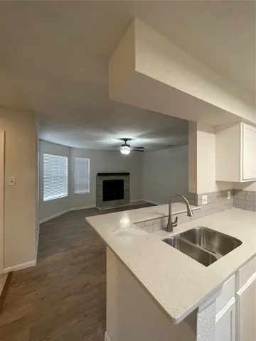 a kitchen with granite countertop a sink and a stove top oven with wooden floor