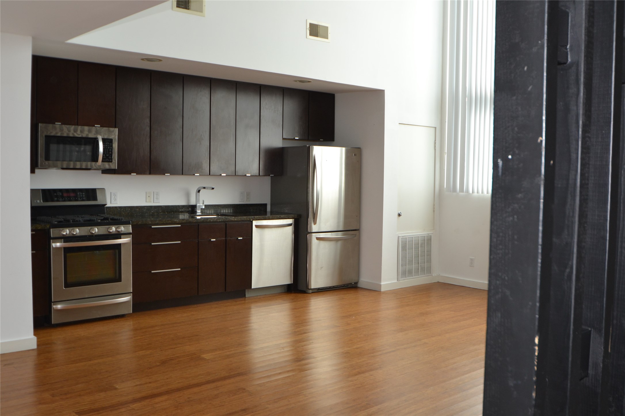 1316 Cleveland Street, Unit C Houston, TX 77019 - Photo 18 of 38 a kitchen with stainless steel appliances granite countertop a stove a refrigerator and a sink with wooden floor