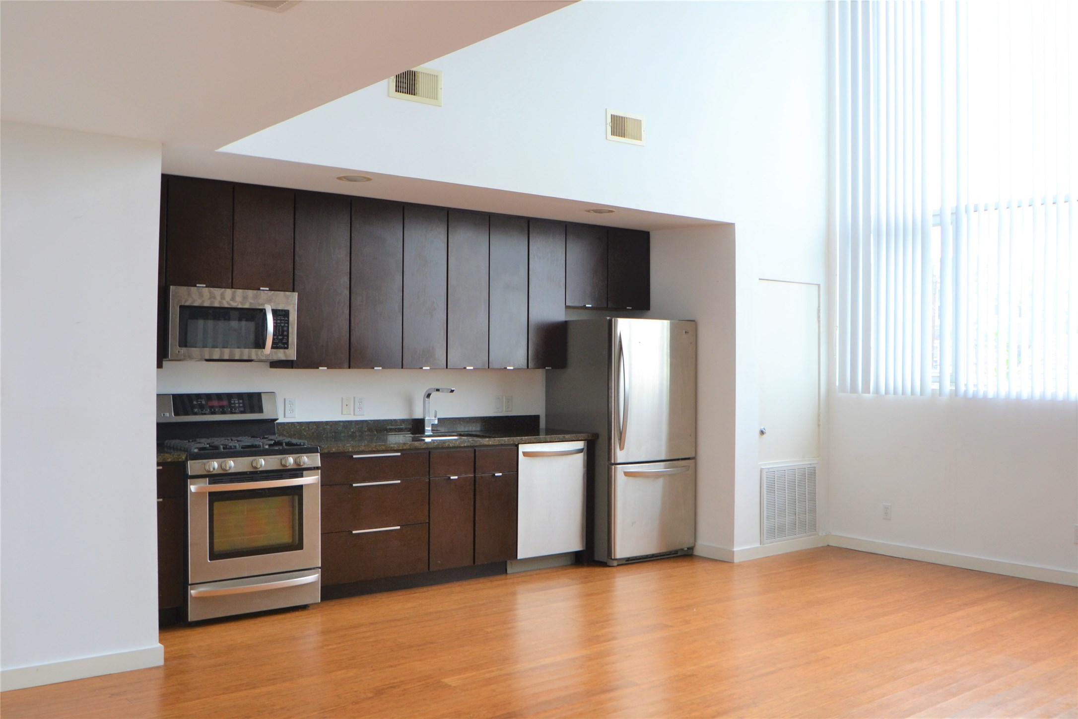 1316 Cleveland Street, Unit C Houston, TX 77019 - Photo 6 of 38 a kitchen with stainless steel appliances granite countertop a stove top oven a refrigerator and a sink with wooden floor