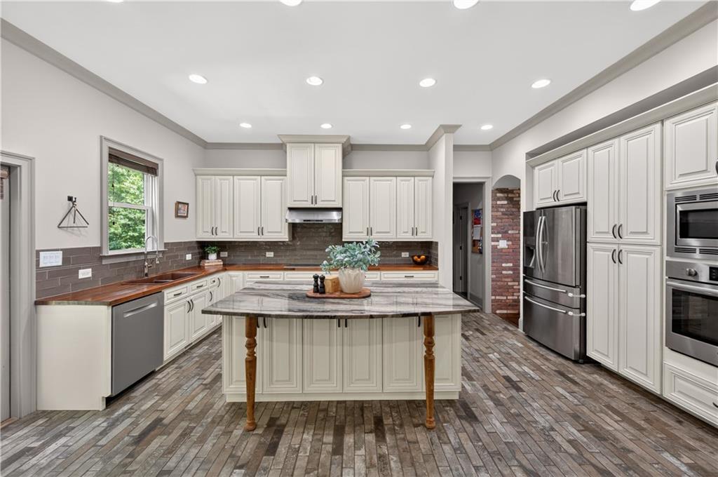 632 Geiger Road Jefferson, GA 30549 - Photo 18 of 55 a kitchen with stainless steel appliances granite countertop a stove top oven a refrigerator a sink and dishwasher with wooden floor