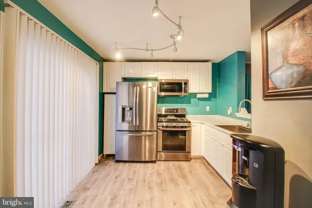 a kitchen with granite countertop a refrigerator a stove top oven a sink and dishwasher