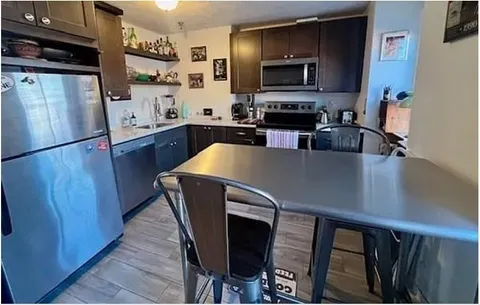 a kitchen with stainless steel appliances a refrigerator a stove a sink cabinets and a dining table