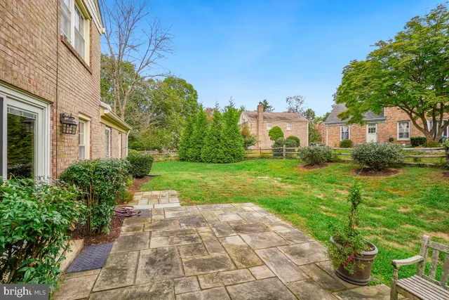 a view of a white house with a big yard plants and large trees