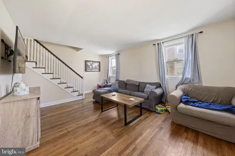 a living room with furniture and a dining table with wooden floor