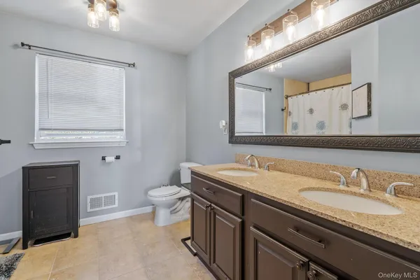 a bathroom with a granite countertop sink a toilet and a mirror
