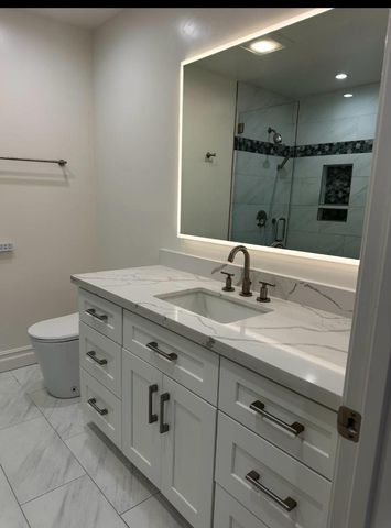 a bathroom with a granite countertop sink a toilet and a mirror
