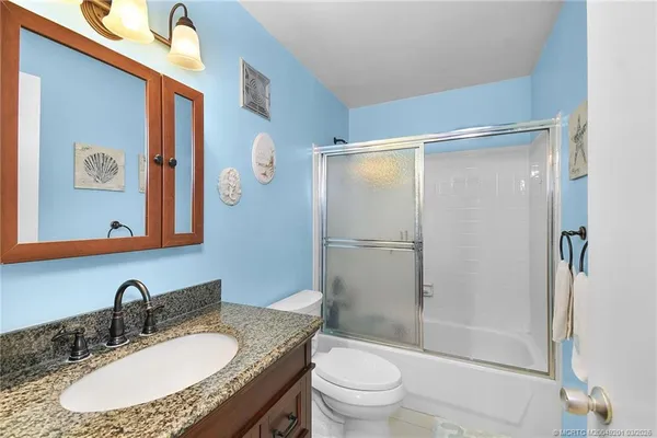 a bathroom with a granite countertop sink toilet and shower