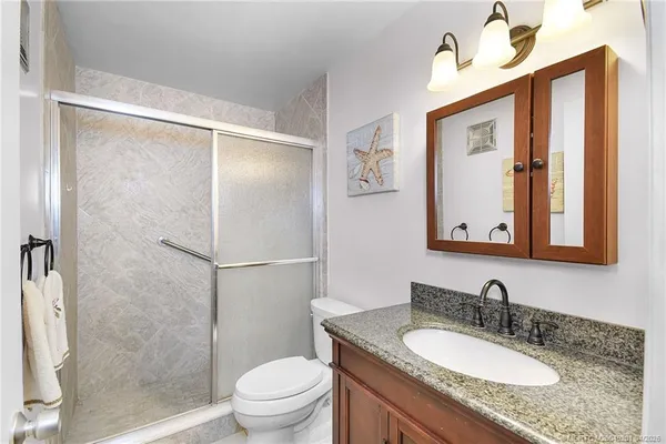 a bathroom with a granite countertop sink toilet and shower