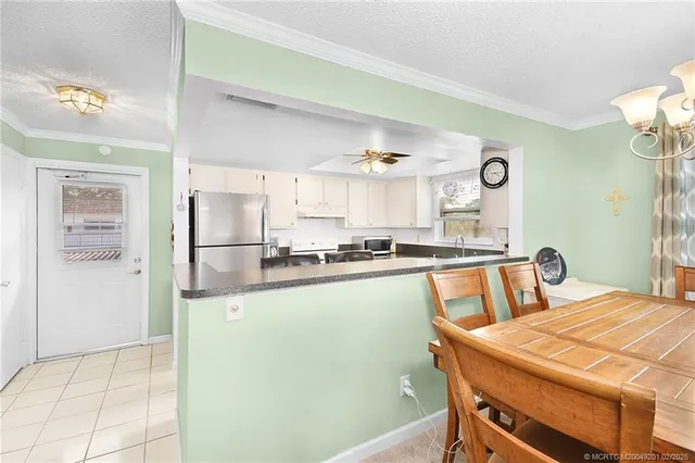 a kitchen with stainless steel appliances granite countertop a sink a stove a refrigerator a microwave oven with white cabinets and wooden floor