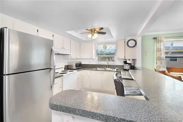 a kitchen with stainless steel appliances granite countertop a refrigerator a sink a stove a dining table and chairs