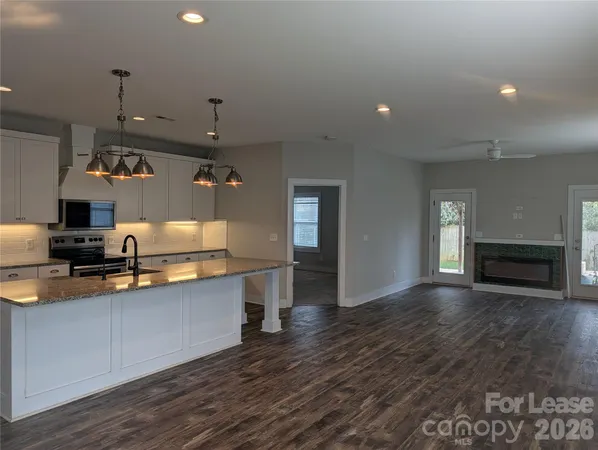 a large kitchen with stainless steel appliances a large counter top a stove and a wooden floors