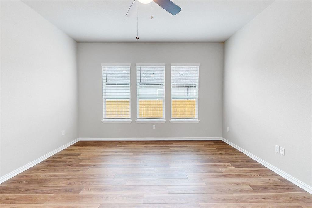 4907 Escape Rivera Drive Austin, TX 78747 - Photo 23 of 28 Natural light floods this spacious room, featuring modern wood flooring and a refreshing ceiling fan.