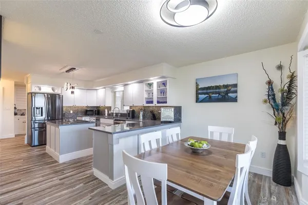 a kitchen with stainless steel appliances granite countertop a refrigerator a stove a sink dishwasher and a dining table with wooden floor