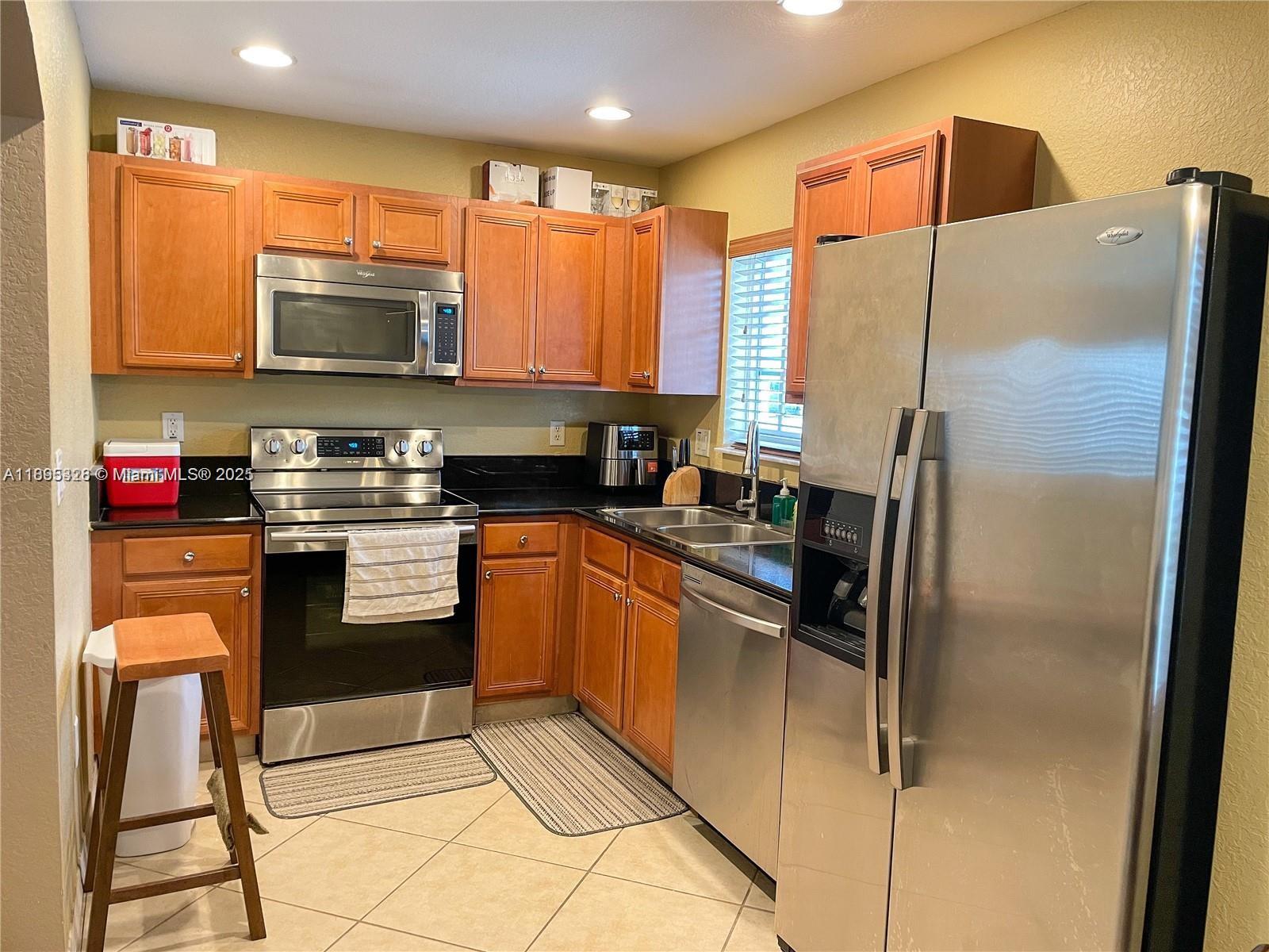 5907 London Lane, Unit 5907 Tamarac, FL 33321 - Photo 2 of 10 a kitchen with stainless steel appliances granite countertop a refrigerator a stove a sink a dining table and chairs with wooden floor