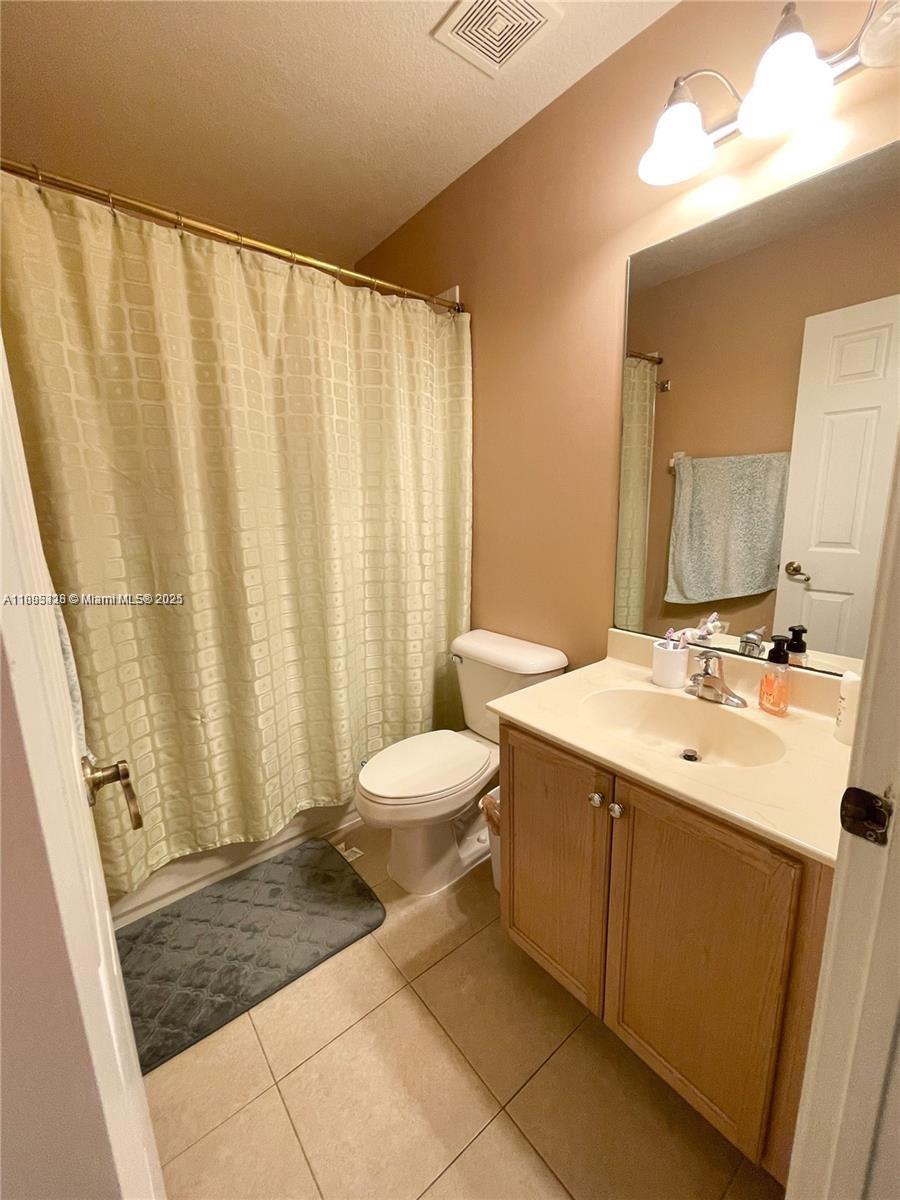 5907 London Lane, Unit 5907 Tamarac, FL 33321 - Photo 6 of 10 a bathroom with a sink a toilet a mirror and shower curtain