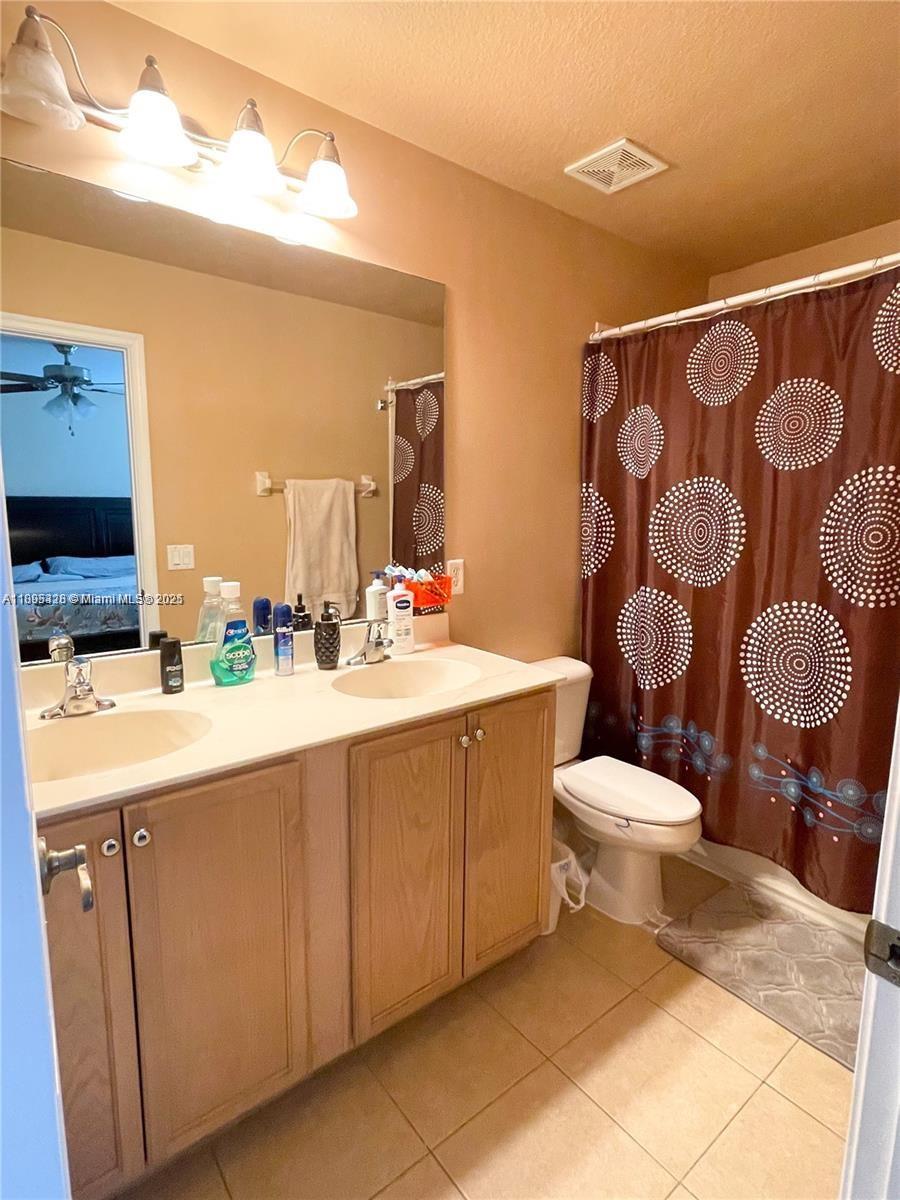 5907 London Lane, Unit 5907 Tamarac, FL 33321 - Photo 8 of 10 a bathroom with a sink a toilet and mirror