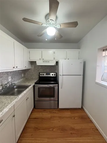 a kitchen with stainless steel appliances granite countertop a refrigerator a stove a sink and white cabinets