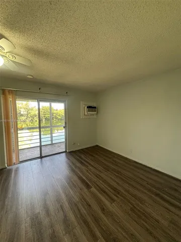 a view of an empty room and wooden floor and a window