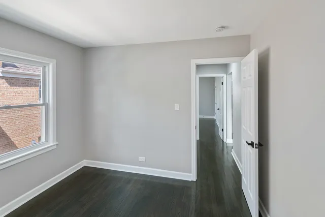an empty room with wooden floor and a window