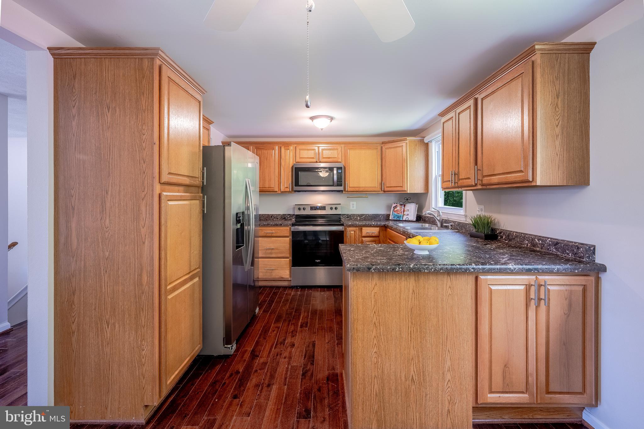 1784 Valleyside Drive Frederick, MD 21702 - Photo 8 of 42 a kitchen with granite countertop wooden cabinets and a refrigerator