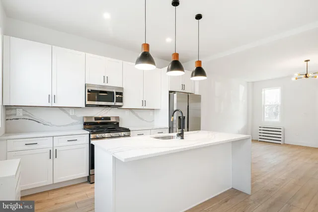 a kitchen with stainless steel appliances kitchen island a white cabinets and a wooden floor