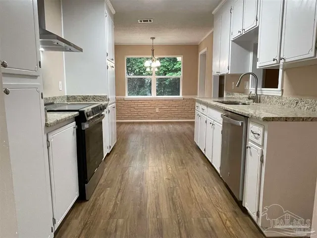 a kitchen with stainless steel appliances hardwood floor sink stove and wooden cabinets