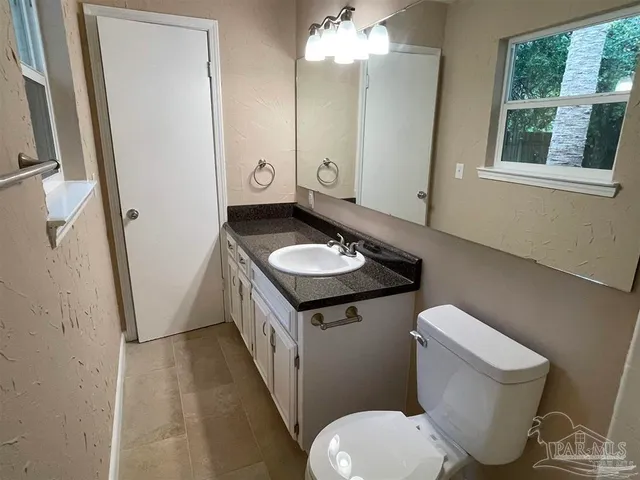 a bathroom with a granite countertop toilet sink and mirror